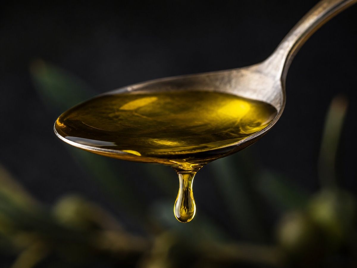 Olio extravergine di oliva in primo piano, con una goccia dorata in sospeso